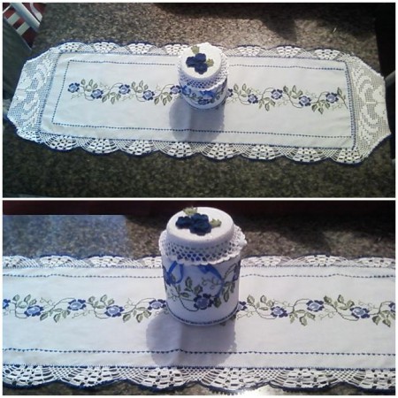 Caminho de Mesa Floral: bordado em ponto cruz com tons de azul e verde, todo contornado e finalizado com crochê, detalhe para o bico branco em formato de flor. Pote Floral: coberto com tecido e bordado em ponto cruz, finalizado com 3 flores de crochê azul